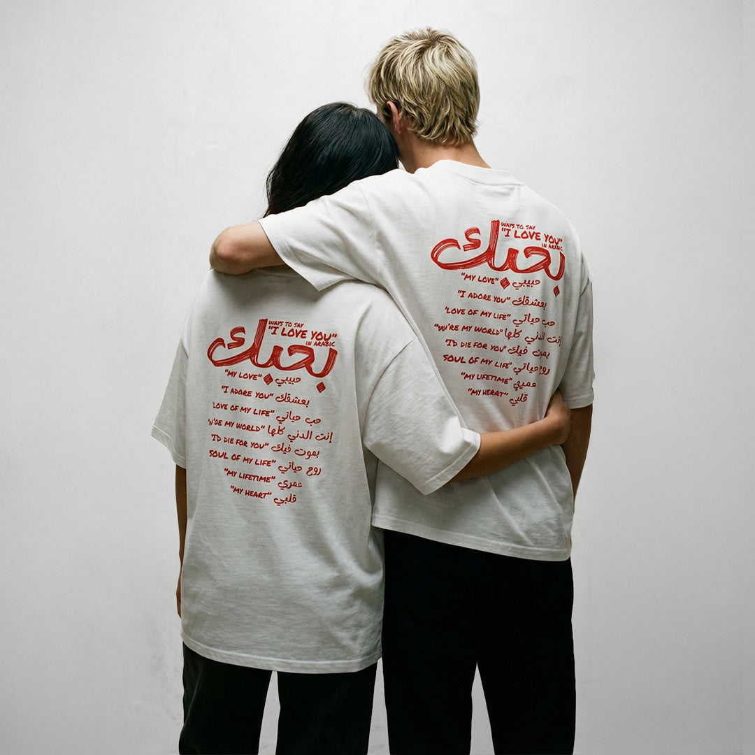 due ragazzi indossano magliette unisex oversize bianche con scritta rossa in inglese e arabo ways to say i love you in arabic - Totally Random®