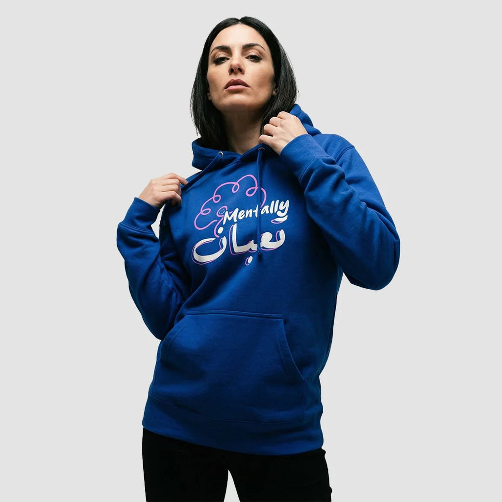 ragazza indossa felpa unisex blu con cappuccio e design di un cervello rosa e scritta bianca in inglese e arabo mentally تعبان - Totally Random®
