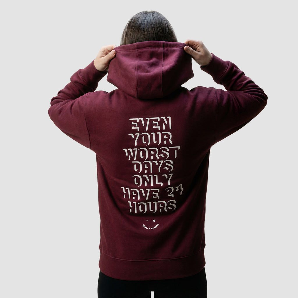 uomo indossa felpa unisex bordeaux con cappuccio e scritta bianca sulla schiena even your worst days only have 24 hours - Totally Random®
