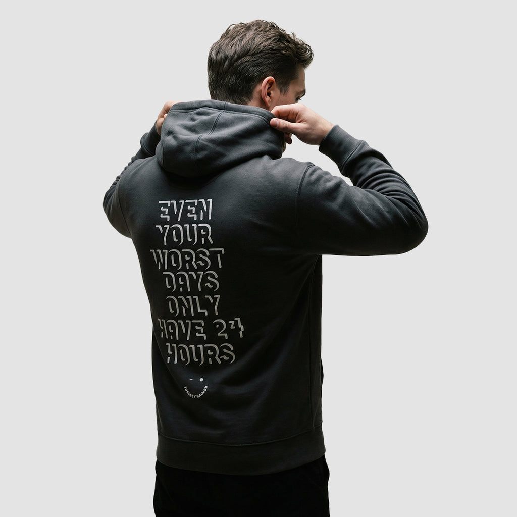 uomo indossa felpa unisex grigio scuro con cappuccio e scritta bianca sulla schiena even your worst days only have 24 hours - Totally Random®