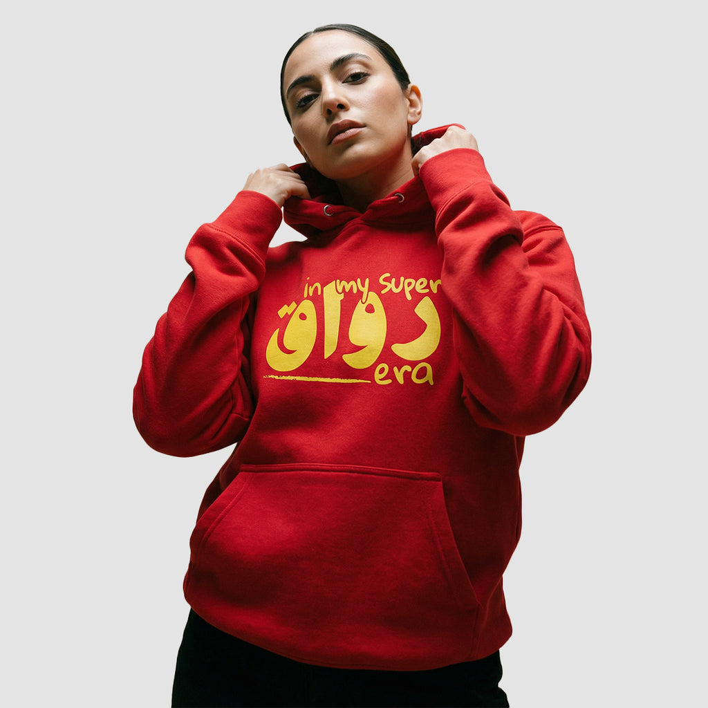 ragazza indossa felpa unisex rossa con cappuccio e scritta gialla in inglese e arabo in my super chill era - Totally Random®