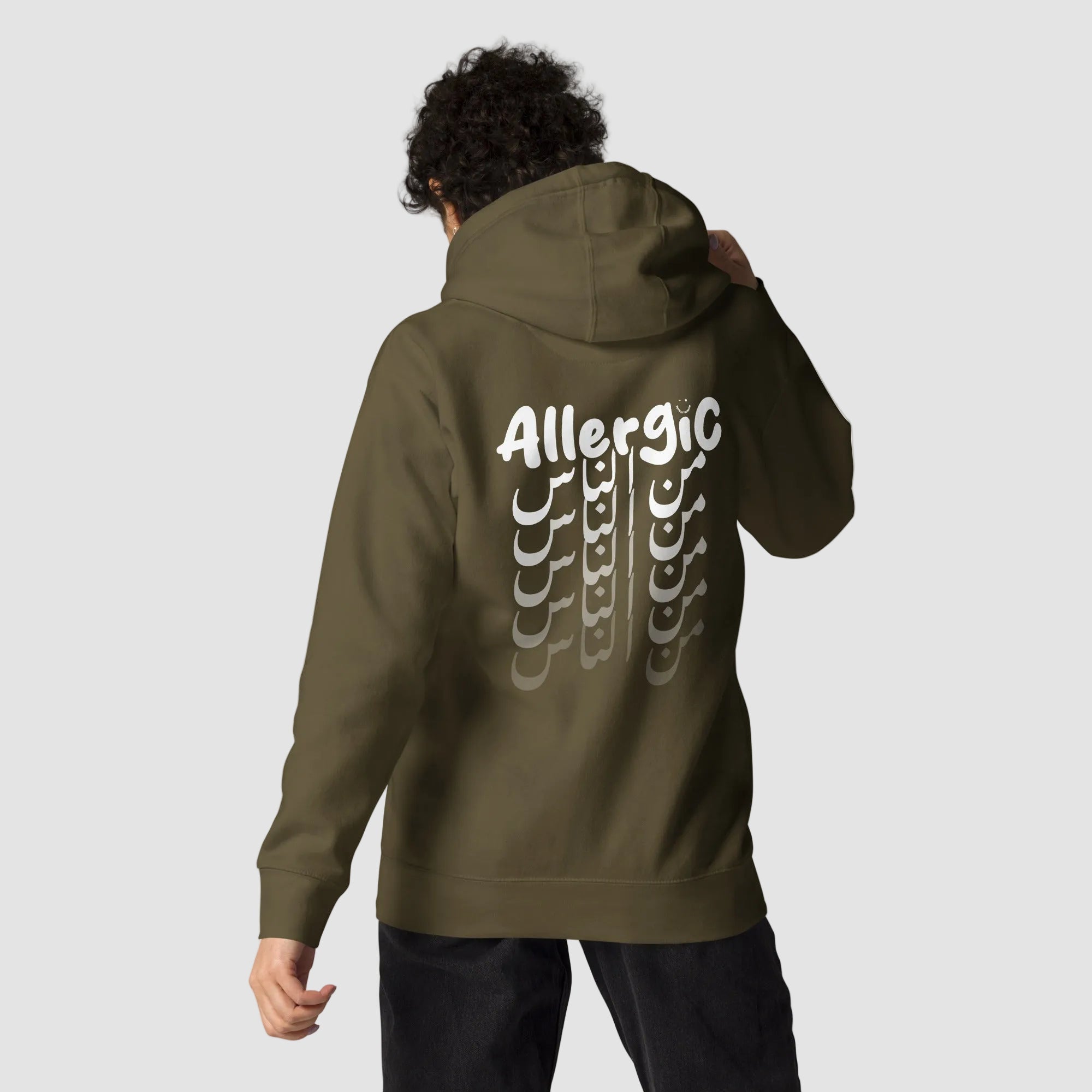 ragazza indossa felpa unisex verde militare con cappuccio e scritta bianca in inglese ed arabo sulla schiena allergic من الناس - Totally Random®