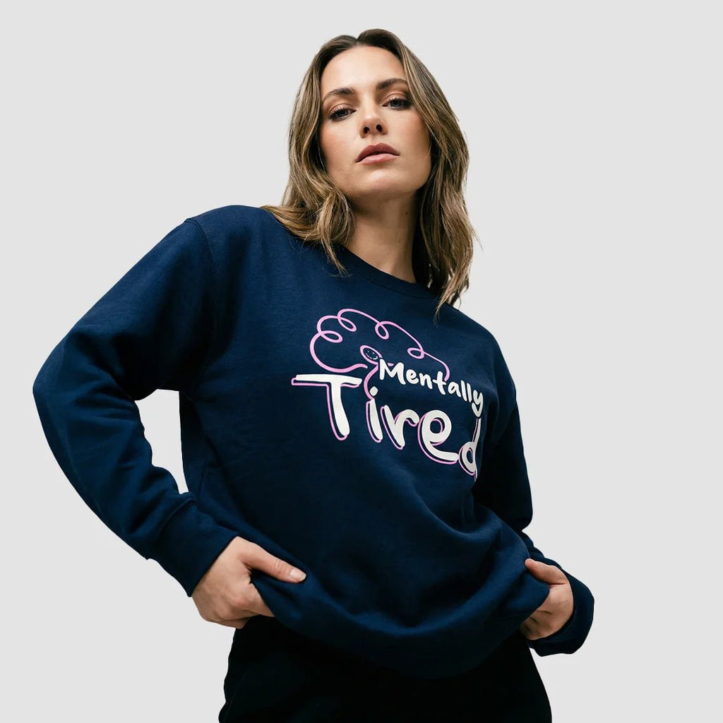 ragazza indossa felpa unisex girocollo blu navy con design di un cervello rosa e scritta bianca mentally tired - Totally Random®