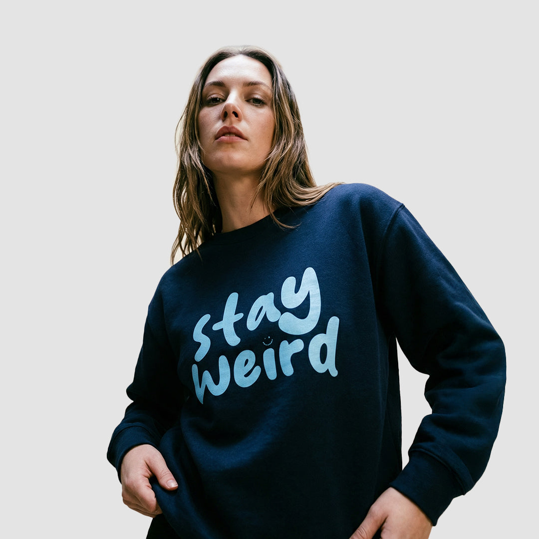 ragazza indossa felpa unisex girocollo blu navy con scritta azzurra in inglese stay weird - Totally Random®