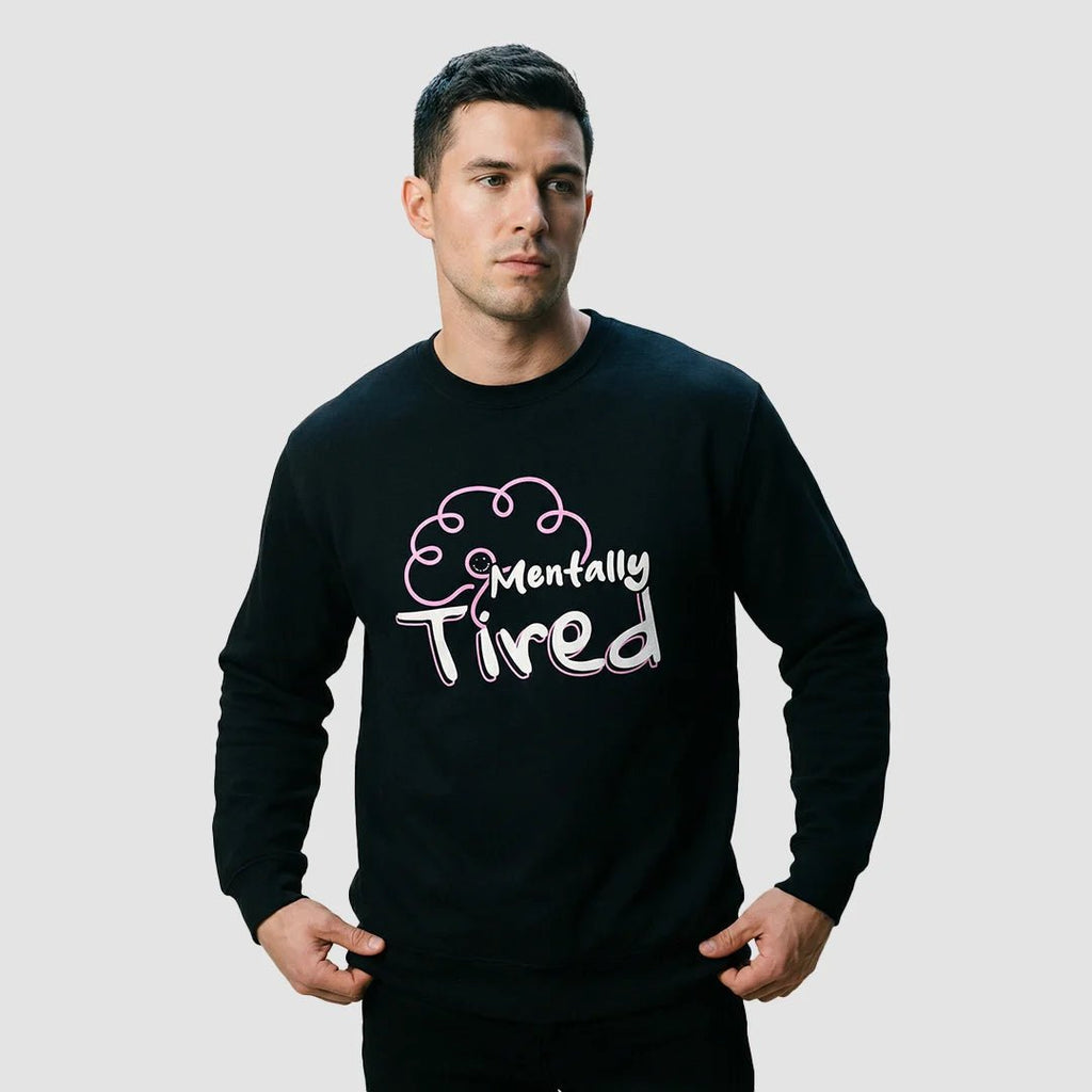 uomo indossa felpa unisex girocollo nera con design di un cervello rosa e scritta bianca mentally tired - Totally Random®