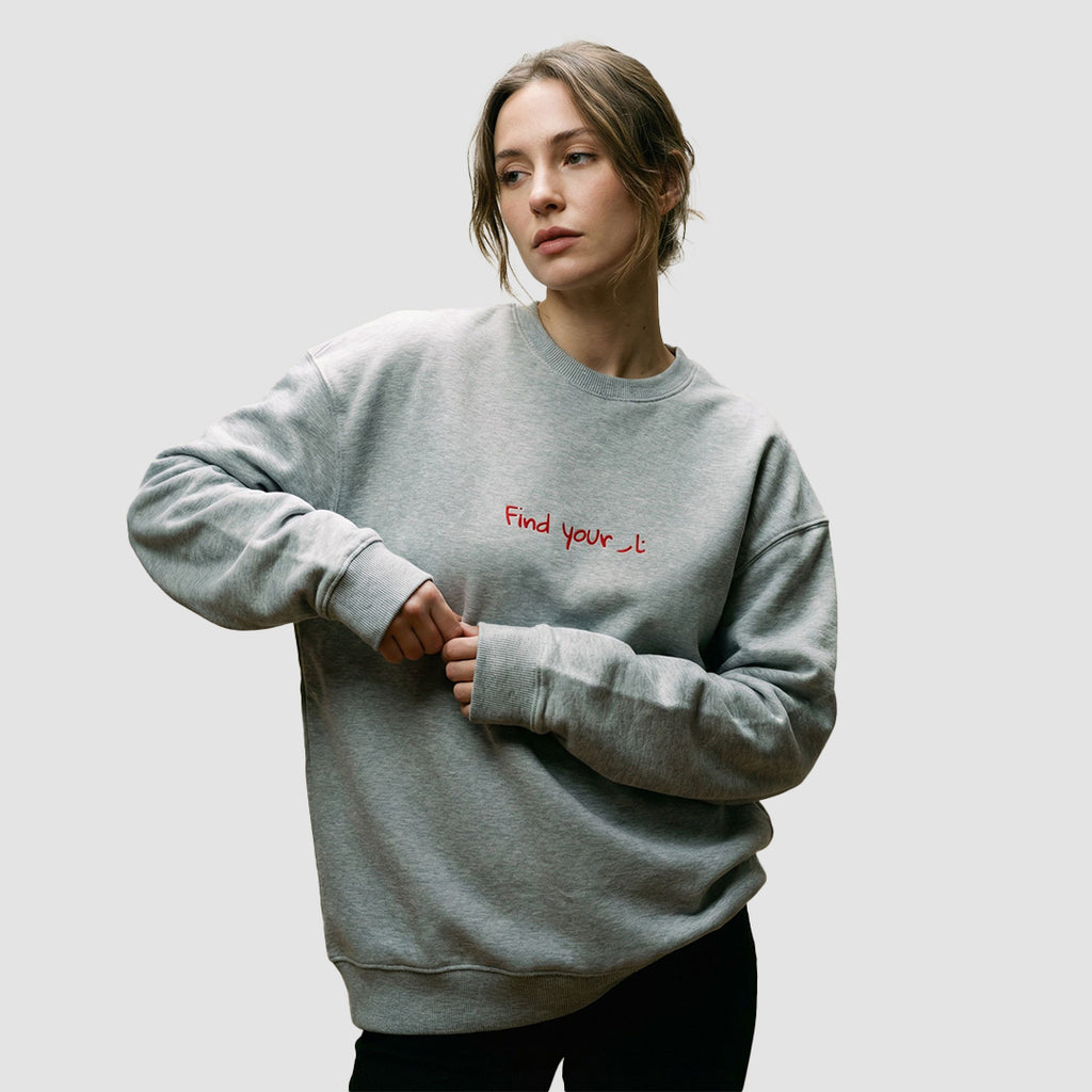 modella indossa felpa unisex oversize grigia con scritta rossa in inglese e arabo find your fire - Totally Random®