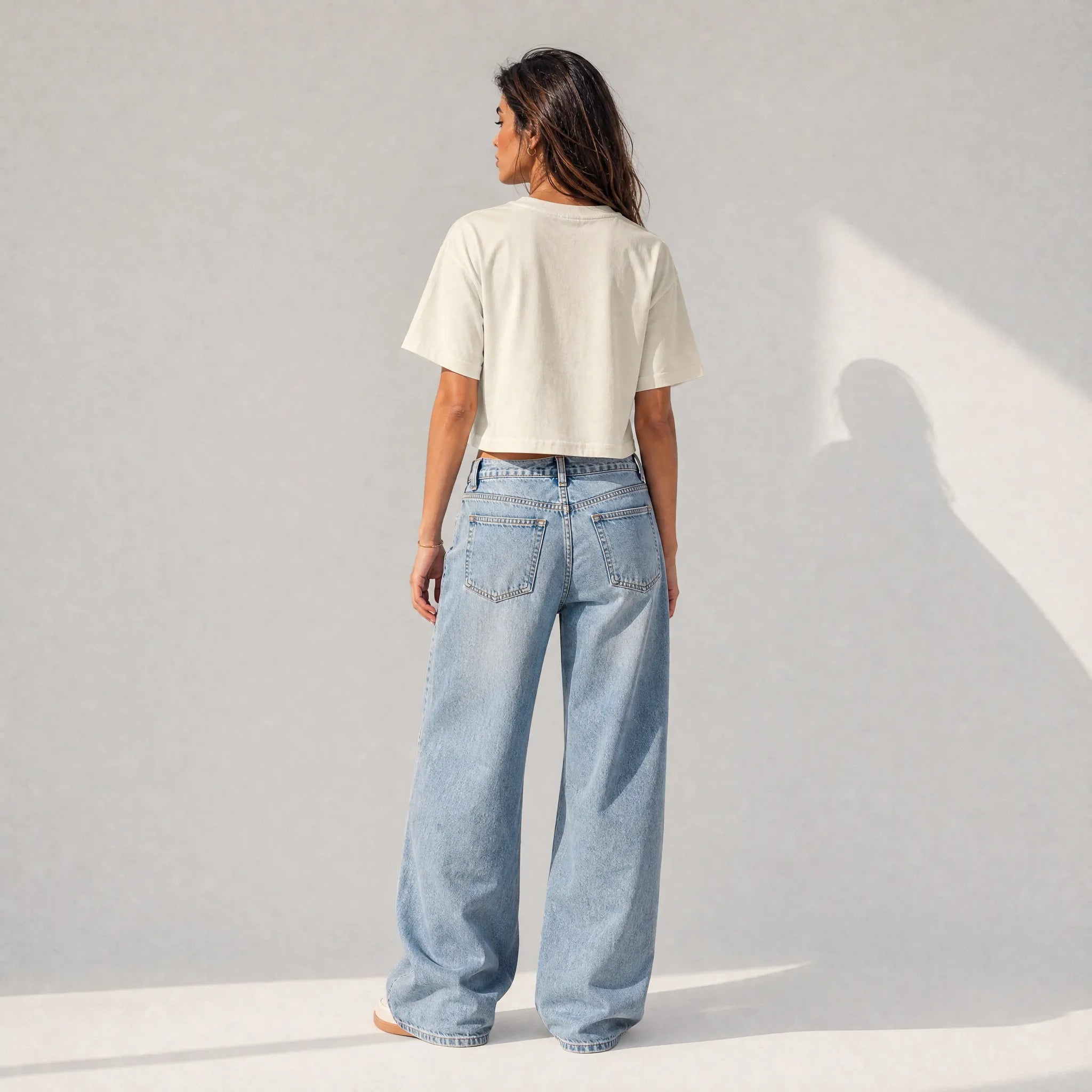 vista posteriore di una donna con outfit streetwear che indossa una cropped t-shirt crema totally random con design today مالي خلق