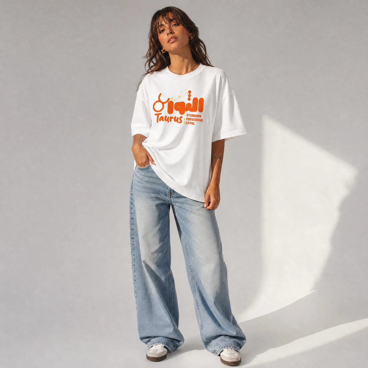 donna con outfit streetwear che indossa una t-shirt bianco oversize totally Random con design oroscopo taurus الثور, stubborn possessive loyal